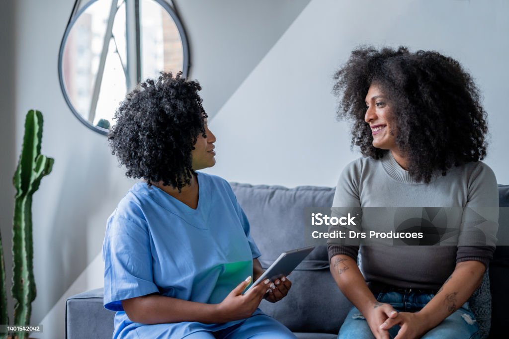 Black nurse consulting trans woman at home Transgender Person Stock Photo