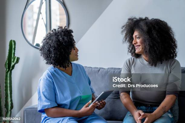 Black Nurse Consulting Trans Woman At Home Stock Photo - Download Image Now - Transgender Person, LGBTQIA People, Doctor