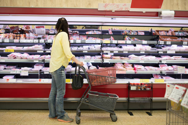 una donna che fa la spesa in un supermercato - price gouging foto e immagini stock