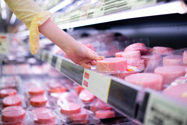 la main d’une femme ramassant du jambon dans un supermarché - price gouging photos et images de collection