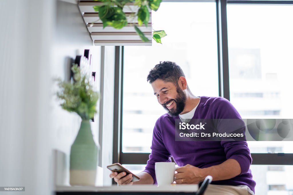 Latin man using smartphone at home Purple Stock Photo