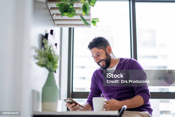 Latin Man Using Smartphone At Home Stock Photo - Download Image Now - Purple, Men, People