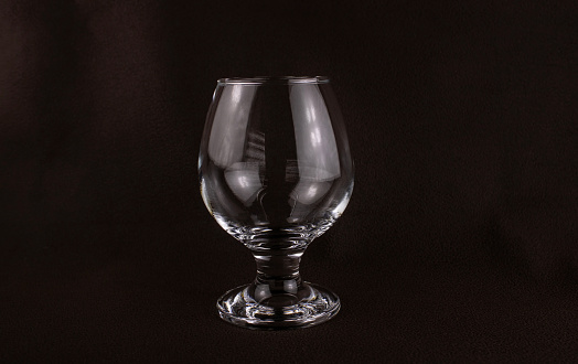 Glass goblet close-up on a dark brown background