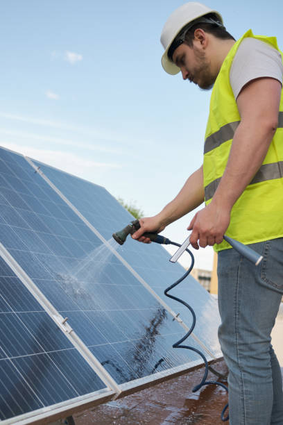 istock Technician cleaning solar panels with a hose. 1401546104