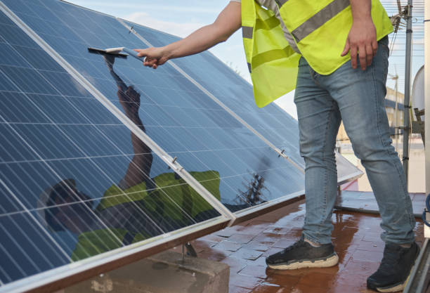 istock Unrecognizable technician cleaning solar panels with a squeegee window cleaner. 1401546196