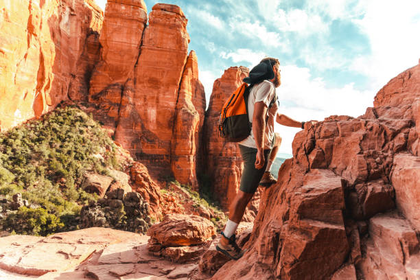 istock Adventurous man with a backpack on his back climbs a rock and looking up 1401546266