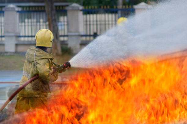 fire fighter Using water mist fire extinguishers to combat oil flames to control fire from spreading firefighters and industrial safety concepts.