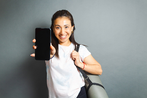 fitness woman showing phone screen while holding yoga mat