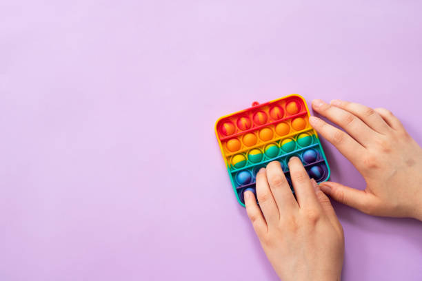 istock Woman using pop it fidget toy on purple background, top view 1401552408