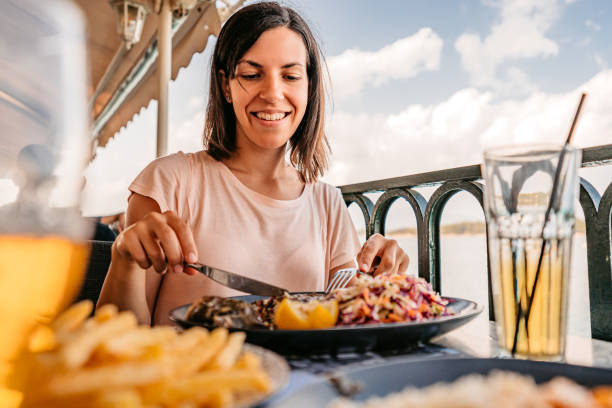 giovane donna che pranza in riva al mare - cibo di mediterraneo foto e immagini stock