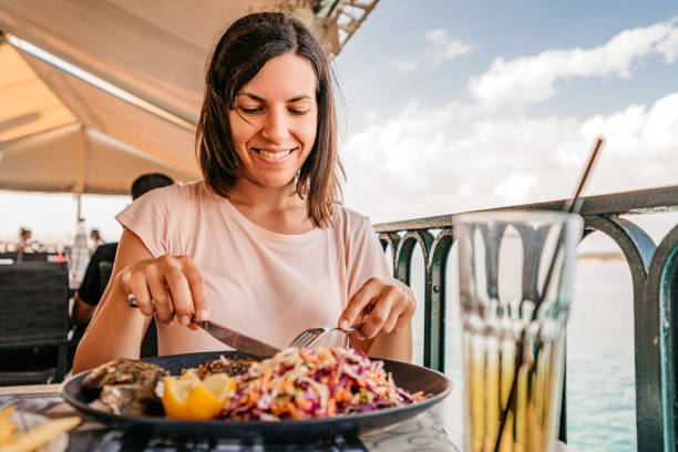 junge frau, die am meer zu mittag isst - krabben meeresfrüchte stock-fotos und bilder