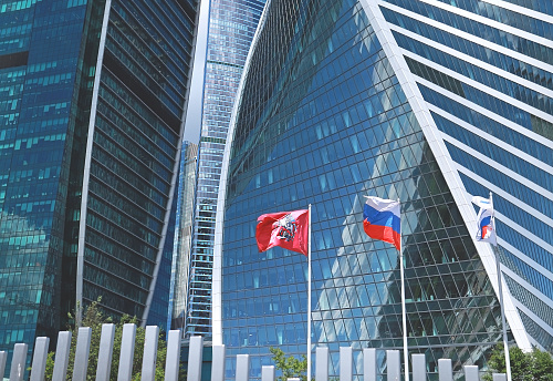 Moscow, Russia - 06.06.2022: The flag of the city of Moscow  and national flag of the Russian Federation waving on poles against the Moscow-city's skyscrapers. The Moscow International Business Center.