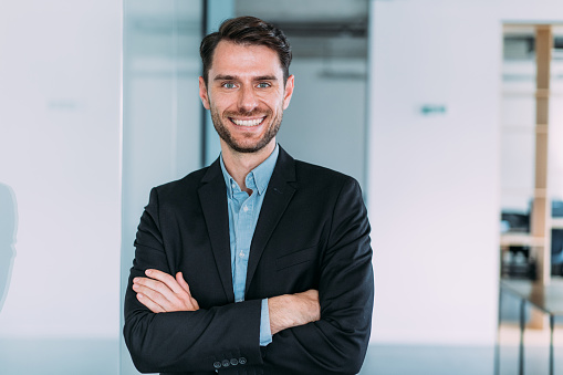 Portrait of a confident businessman in modern office. Shot of young businessman standing with crossed arms and looking at camera.