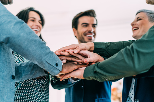 Shot of multi-ethnic group of business people with stacked hands showing unity and teamwork. Successful business people stacking hands in modern office.