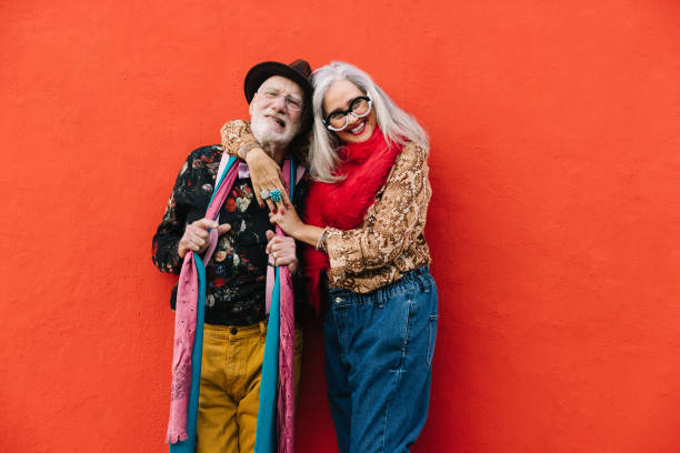 istock Happy elderly couple smiling cheerfully against a red wall 1401557459