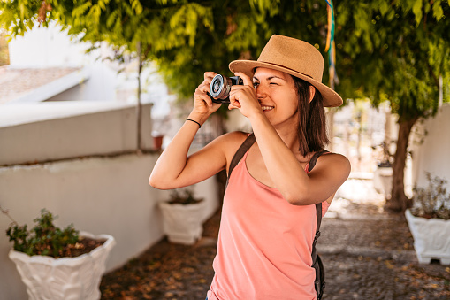 Beautiful young female tourist photographing in Kassiopi in Corfu, Greece.