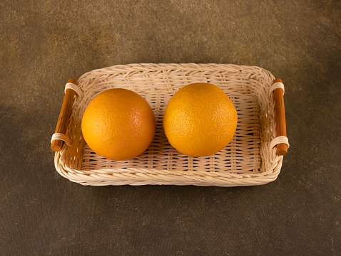wicker bread basket tray with two oranges close up