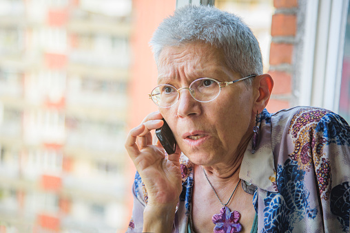 Shocked senior woman can't believe the news she's hearing over her cell phone, shocked and worried