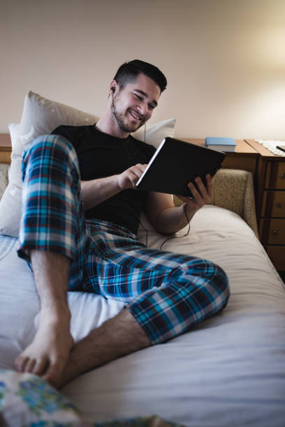 istock Young handsome man laying on bed,resting and use a tablet. 1401571847