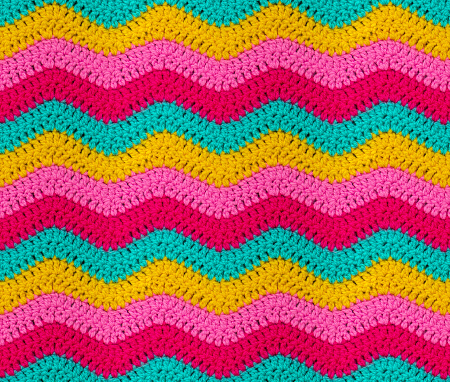 Seamless knitted pattern in the form of zigzags is crocheted with bright multi-colored threads. Acrylic baby yarn.