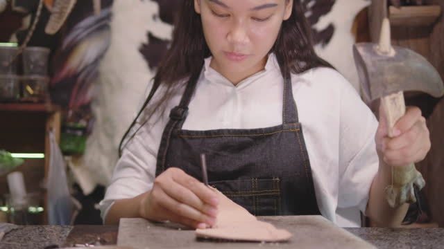 A woman produces leather goods in a studio.