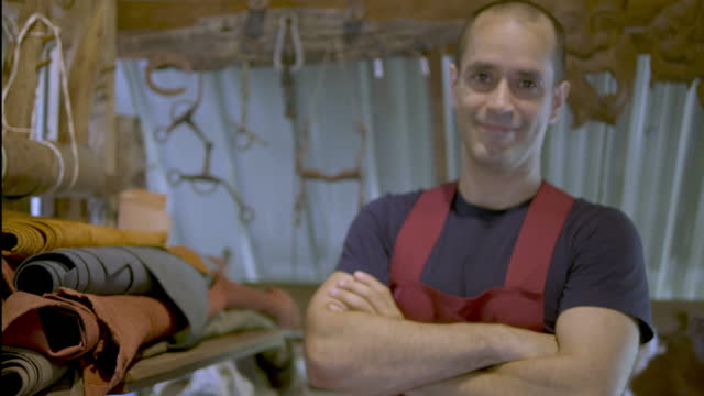 A man stood smiling proudly in a leather studio.