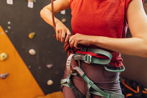 The woman wearing a climbing harness before training indoors