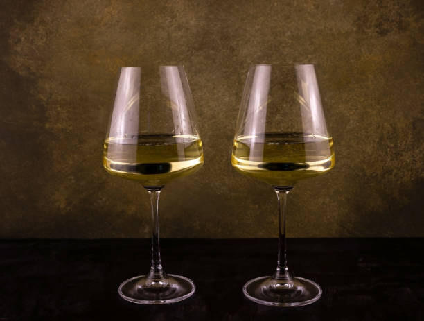 two long-stemmed glasses with white wine on a camouflage background