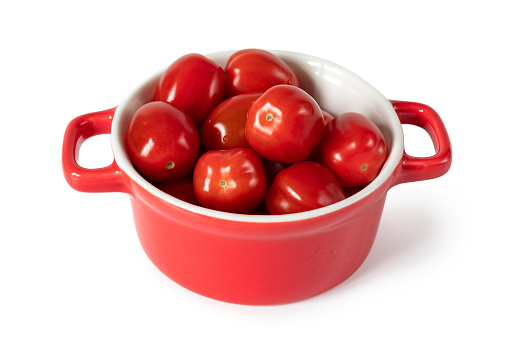 ripe small cherry tomatoes in a red square ceramic baking dish. Isolated on white background with clipping path. Close-up.