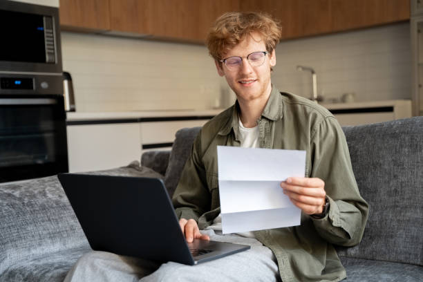 Ginger irish freelance man working with laptop and document at home office stock photo
