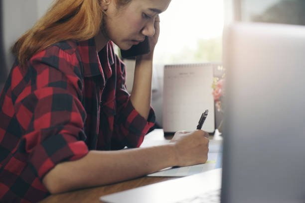 concepto de trabajo desde casa. planificador usando el teléfono y escribiendo para planificar la agenda diaria en el libro del calendario. marca a mano de la mujer y el horario de notas (viaje de vacaciones) en el diario en el mostrador de la oficina de n - working at home calendar laptop women fotografías e imágenes de stock