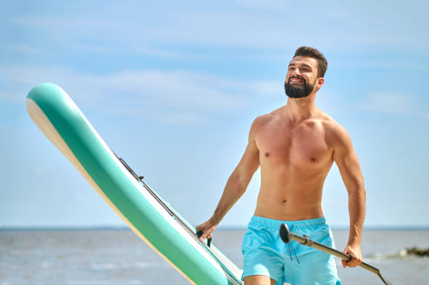 istock A handsome dark-haired man with a kayak on a beach 1401580122
