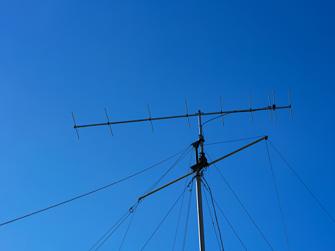 A VHF radio antenna with a stay ropes against blue sky