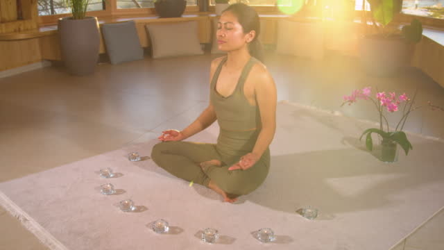 SLOW MOTION: Meditating beautiful young Asian woman in relaxing home atmosphere