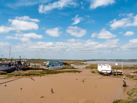 Some old houseboats moored on the mudflats at Old Felixstowe (Felixstowe Ferry) in Suffolk, Eastern England, on a sunny day in May.