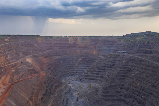 istock Open pit iron ore mining. Drill rigs and excavators in the process . Heavy steel industry initial production chain . Thunderstorm clouds over the quarry. 1401582577