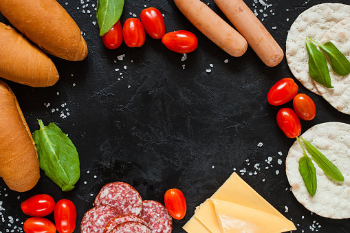 ingredients for a sandwich - sausage, cheese, tomatoes on a table, the top view, selective focus, copy space