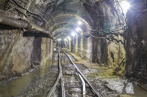 Underground interior of iron ore mine. Train track for loading iron ore and equipment