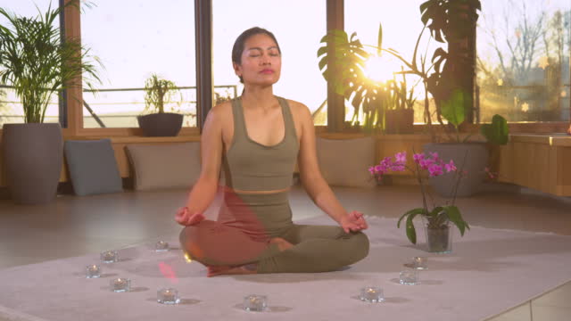 SLOW MOTION: Asian woman meditating in lotus pose practicing breathing technique