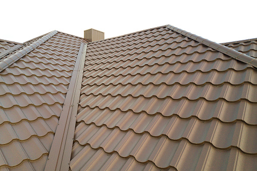 House roof surface covered with brown metal tile sheets.