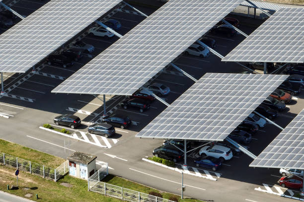 Aerial view of solar panels installed over parking lot with parked cars for effective generation of clean energy Aerial view of solar panels installed over parking lot with parked cars for effective generation of clean energy. solar panels on the roof of building in a city stock pictures, royalty-free photos & images