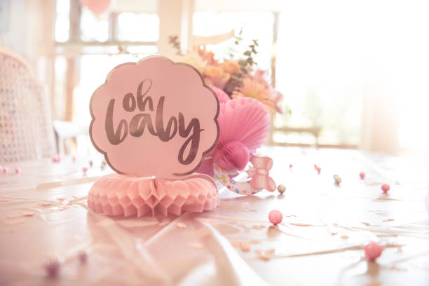 Table with Pink Baby Shower Accessory & flowers in brightly lit room