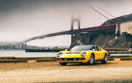 San Fran, CA, USA
11/2/2021
Yellow Lamborghini Miura parked with the Golden Gate bridge in the background with fog