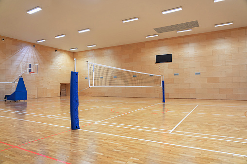 Red de voleibol en un gimnasio vacío con un aro de baloncesto móvil en el fondo photo