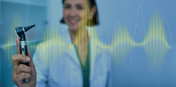 Audiologist with otoscope on sound waves background. Hearing treatment concept