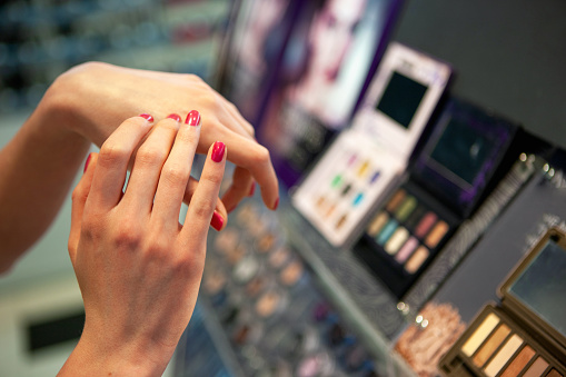 Close-up of woman in department store, trying eye shadow on top of her hand