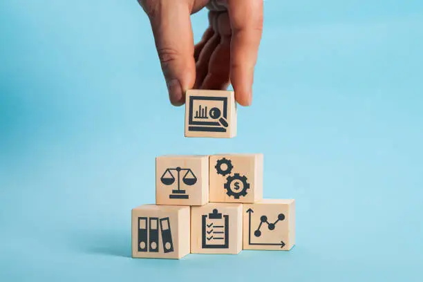 Photo of Examination and evaluation of the financial statements of an organization income statement, balance sheet, cash flow statement. Audit business concept. Holding wooden cubes with audit icon.