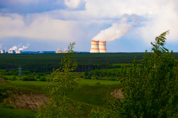 Evening sunset sky scene with dramatic clouds. A nuclear power plant in a field behind a forest. the general plan