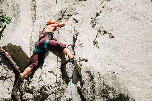 Young woman rock climbing on the cliff