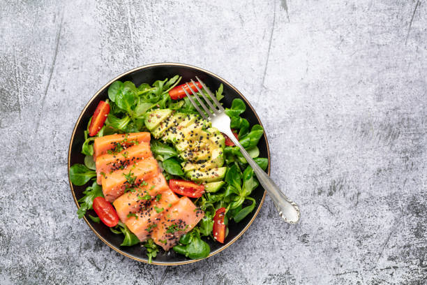 istock Salmon fish fillet with fresh salad, avocado top view. 1401606545